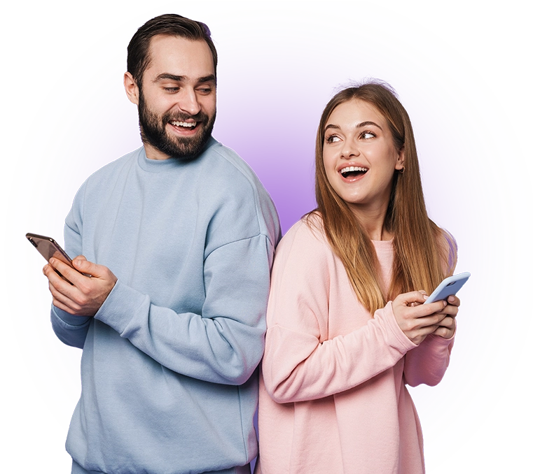 Smiling woman and man, wearing blue and pink, standing back to back, holding their smartphones